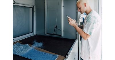 TikToker Everett Williams holding his phone up, filming the process of the Future Finish laser technology creating his customized cheetah print Levi's® denim jeans.