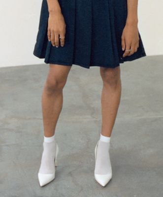 someone wearing white heels and a blue skirt