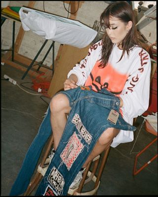Girl sitting with jeans in her hand.