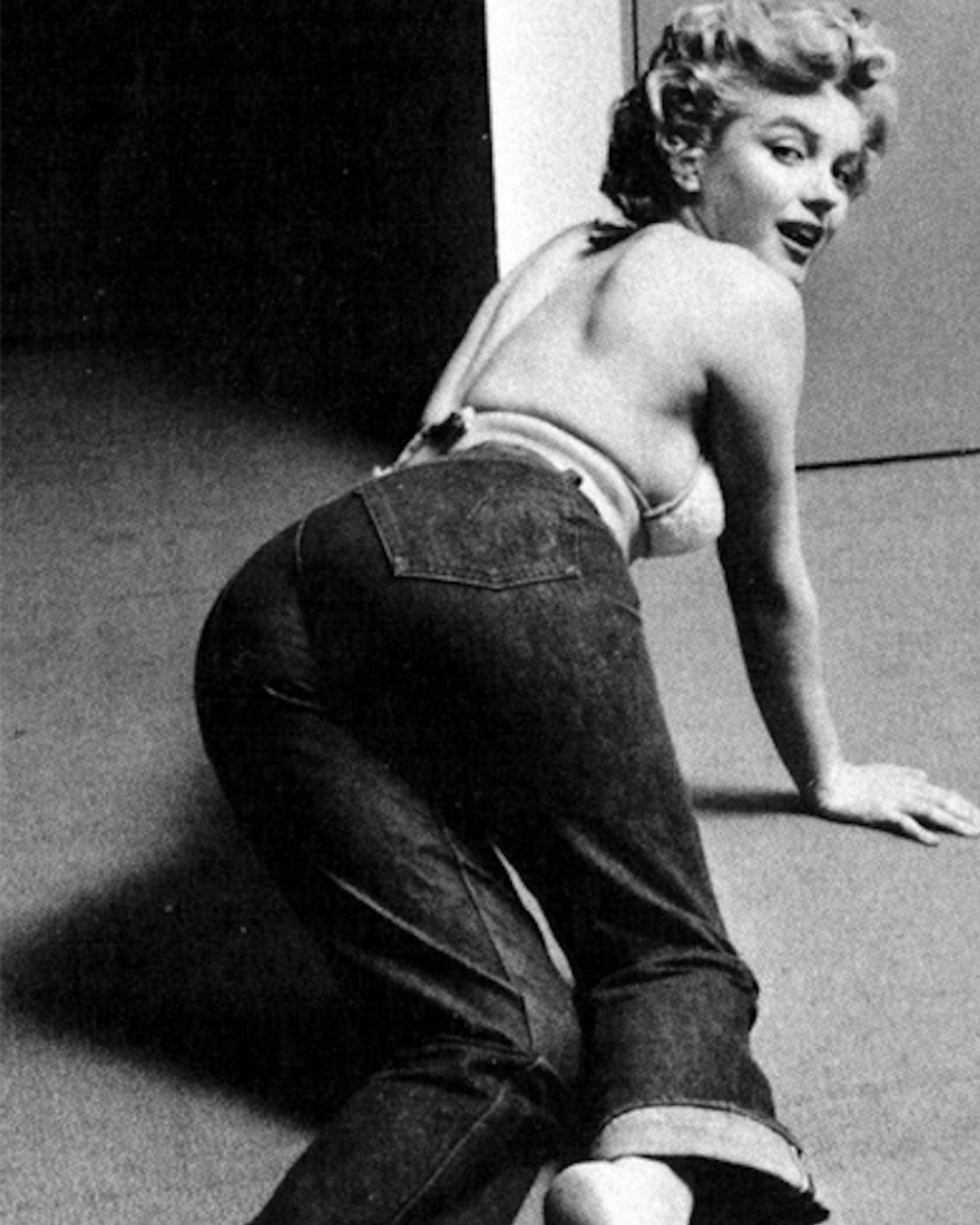 A black and white photo of Marlin Monroe crawling on the floor wearing 501 jeans.