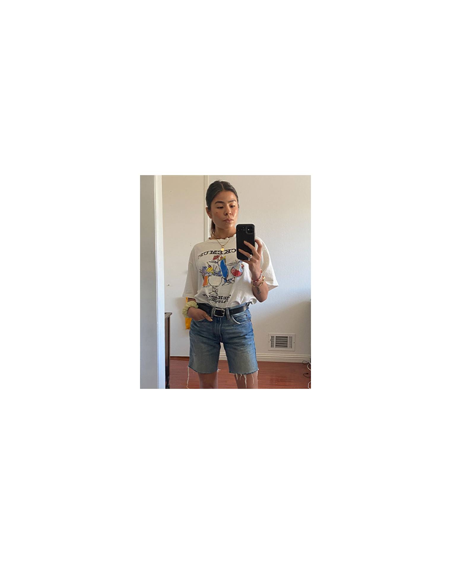 Mirror selfie of Katya Linehan. She is wearing a white graphic tee and cut-off Levi's.