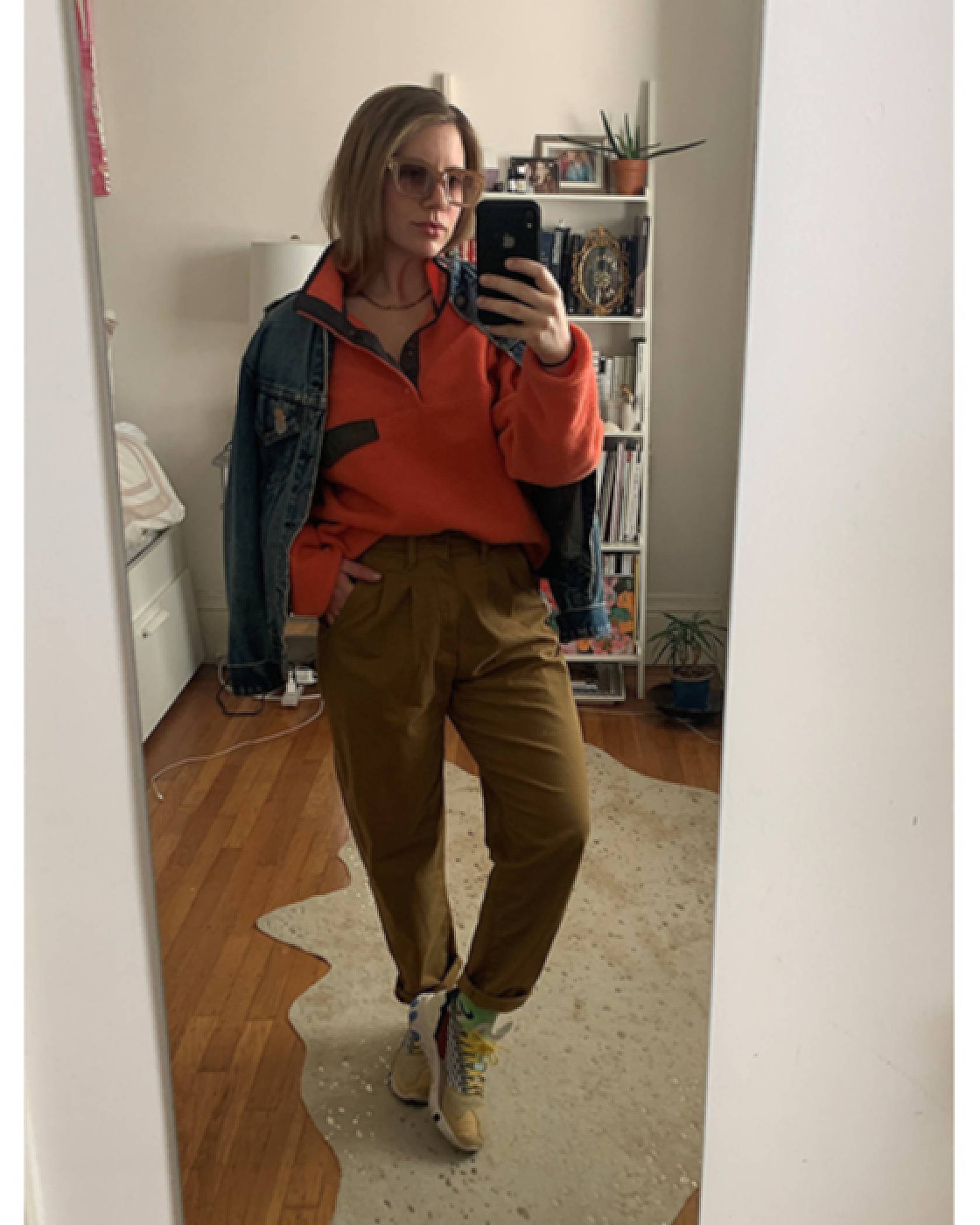 A mirror selfie of Haley Mitgang. She is wearing a red pullover fleece, a Levi's Trucker Jacket, and khaki pleated Balloon pants with sneakers.