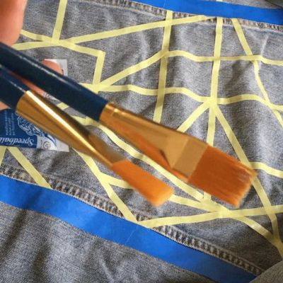 Video of a Levi's® Tailor painting in the outlined geometric design they created for the denim trucker jacket by alternating between silver and gold paint.