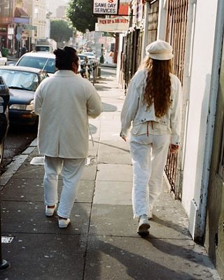 Photo of Gem and Haley walking down a sidewalk in San Francisco. They are both wearing white head-to-toe.
