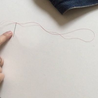 Image of a needle and thread to show how to thread the needle through and leaving a loop on one end.