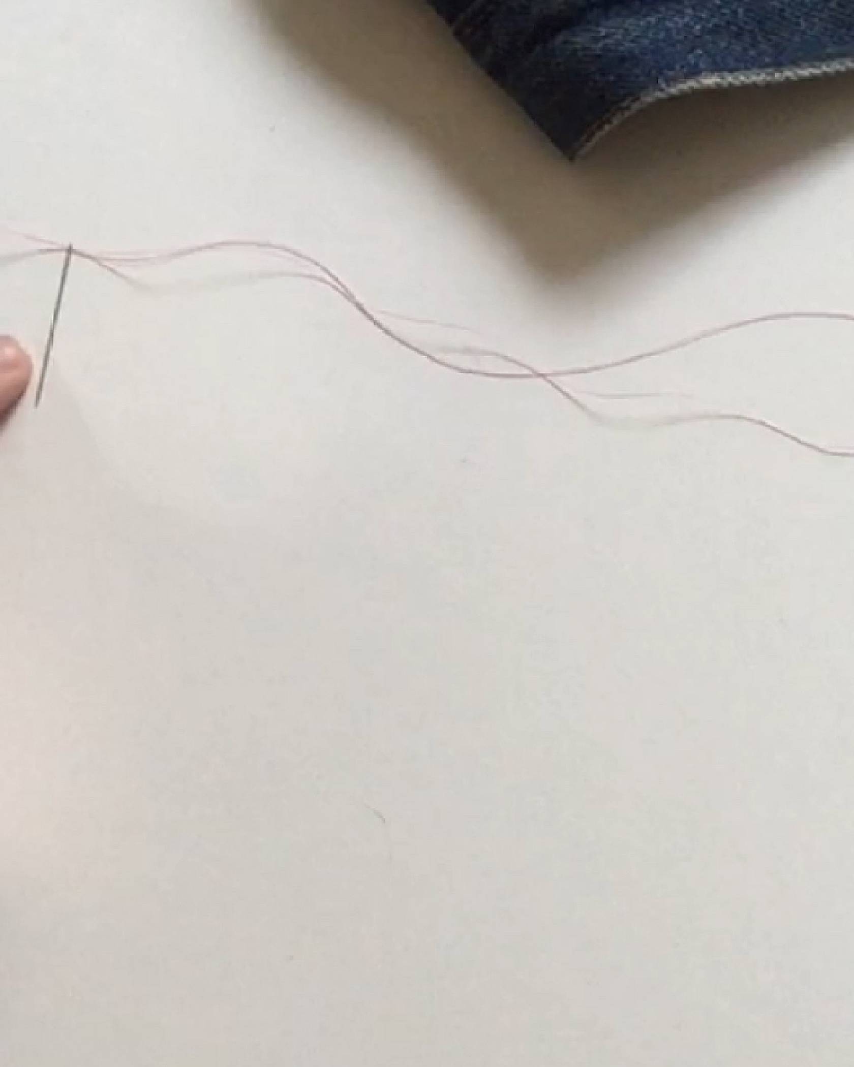 Image of a needle and thread to show how to thread the needle through and leaving a loop on one end.