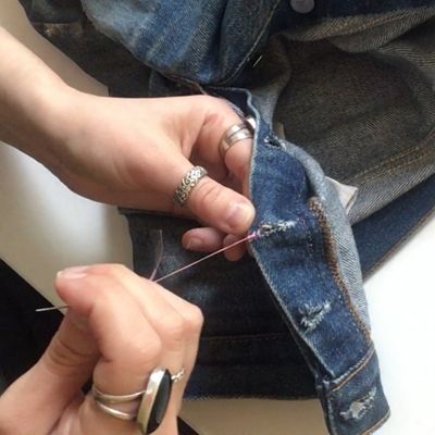 Image of the Levi's® Tailor finishing a stitch with a knot by winding the thread back and forth through the denim jeans.