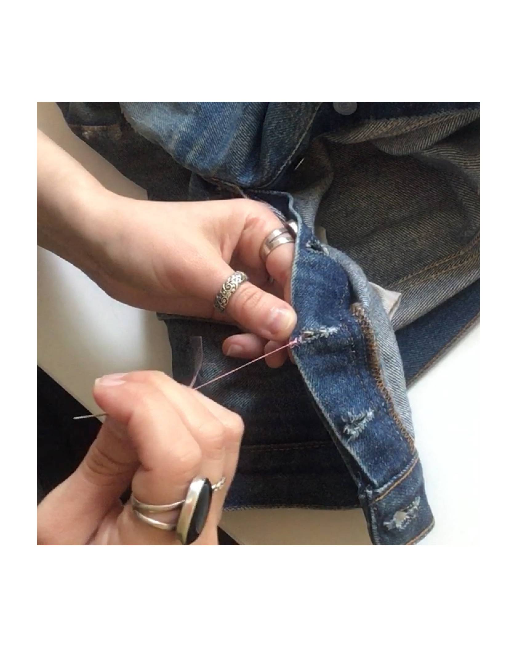 Image of the Levi's® Tailor finishing a stitch with a knot by winding the thread back and forth through the denim jeans.