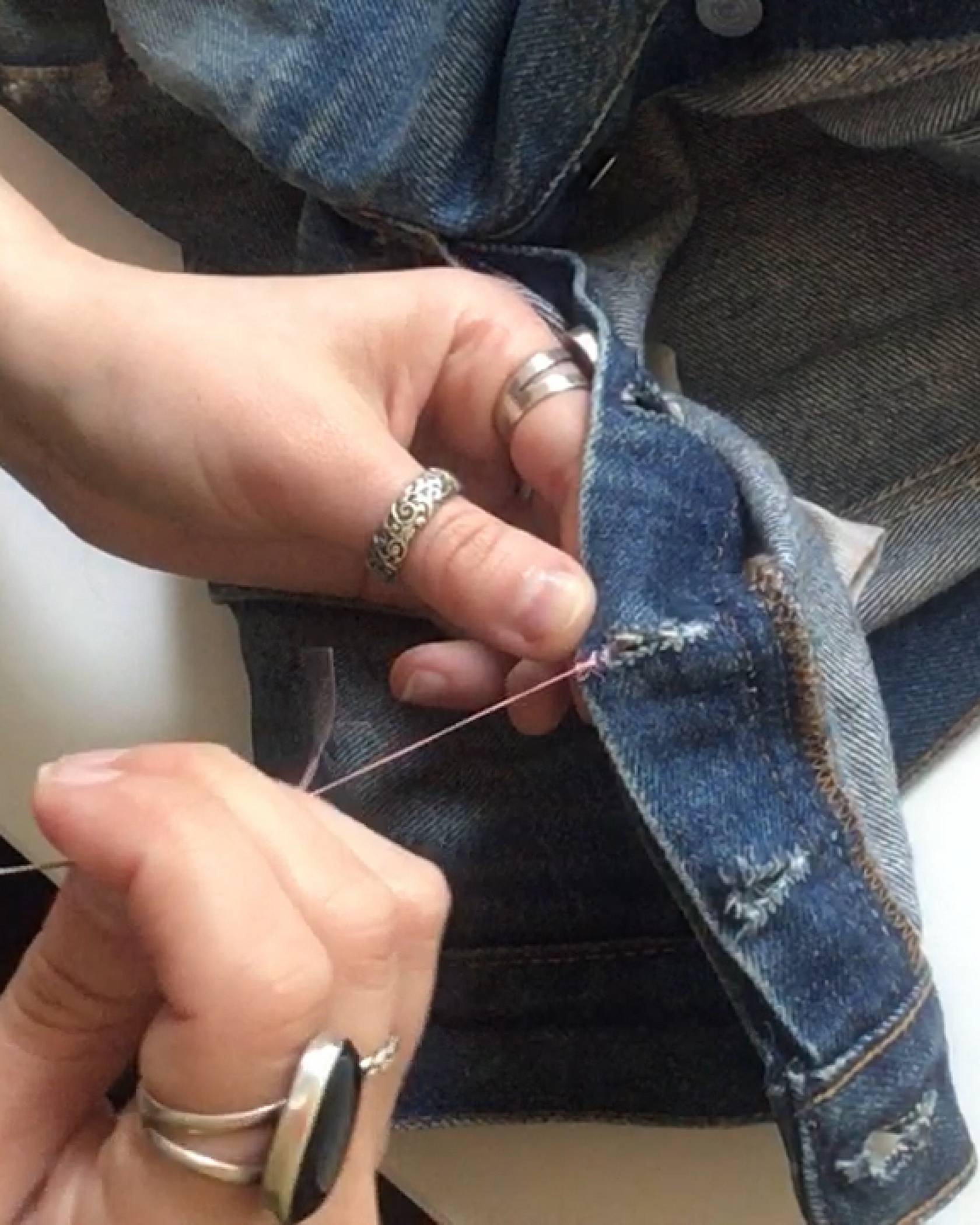 Image of the Levi's® Tailor finishing a stitch with a knot by winding the thread back and forth through the denim jeans.