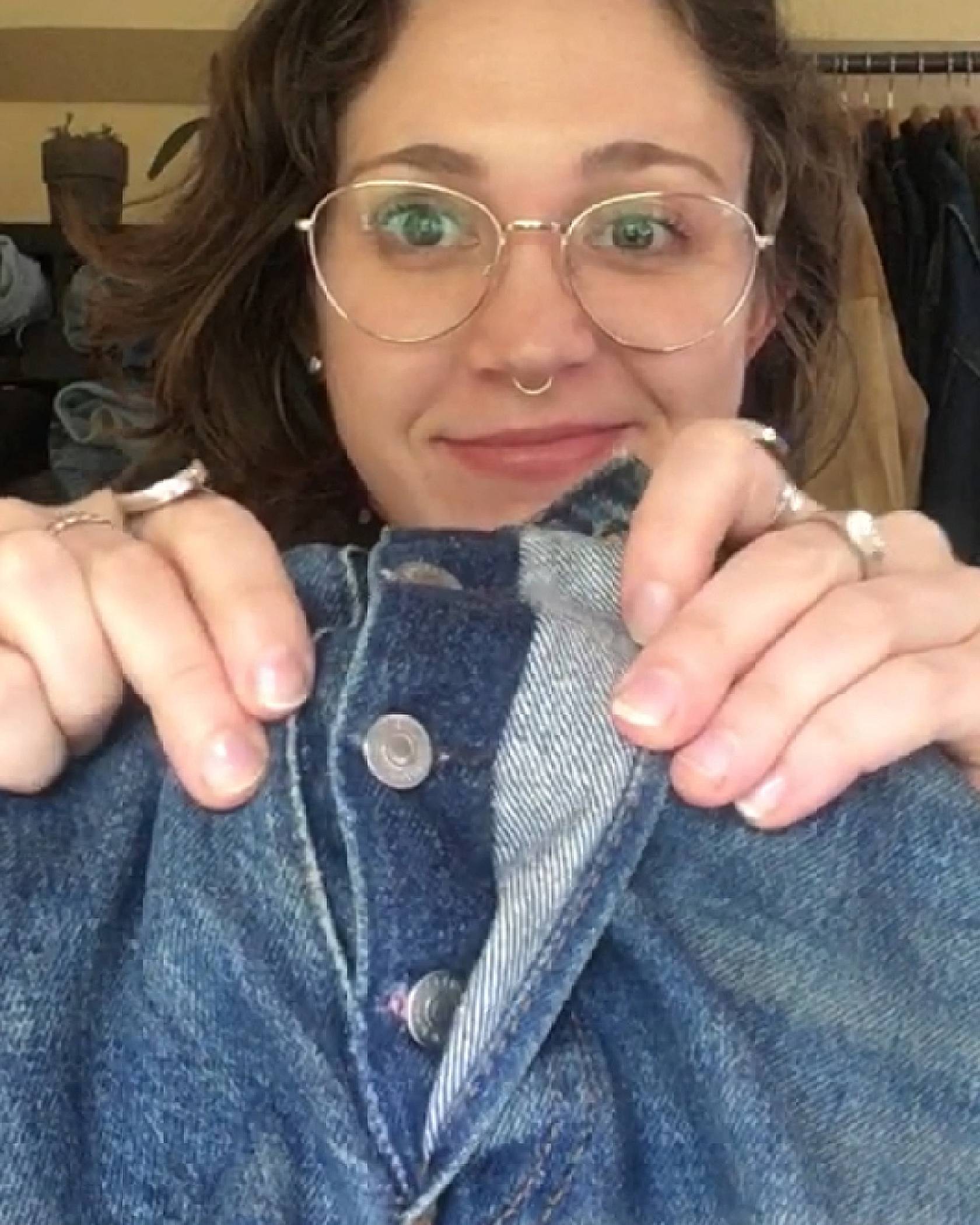 Levi's® Tailor Jen Sharkey holding up a pair of jeans, showing the repaired buttonhole on the button fly of a pair of jeans.