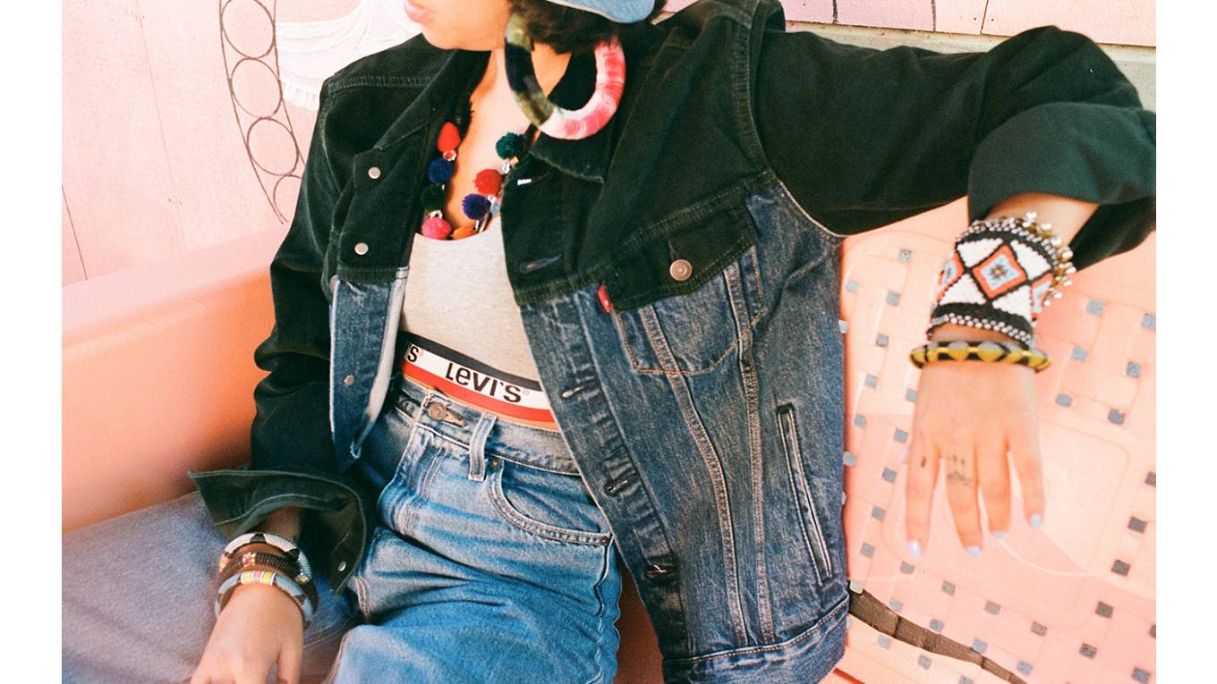 Close-up image of Salomée Souag wearing a Levi's sports bra, Trucker Jacket, and jeans and colorful bracelets.