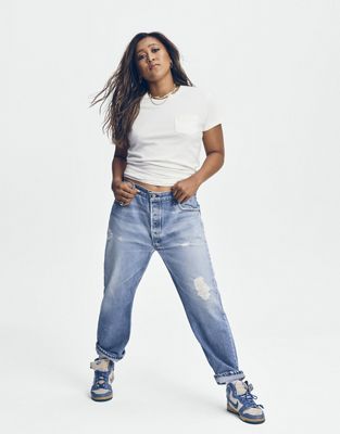 Naomi Osaka standing in blue jeans and a white shirt.