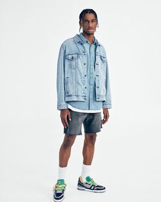 Shai Gilgeous standing with a white background and a light denim jacket.