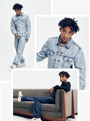 Jaden Smith wearing light blue denim and sitting on a couch in New Balance shoes.