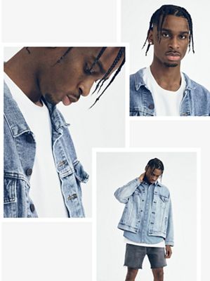 Shai wearing a denim jacket with white shirt looking down at the ground.