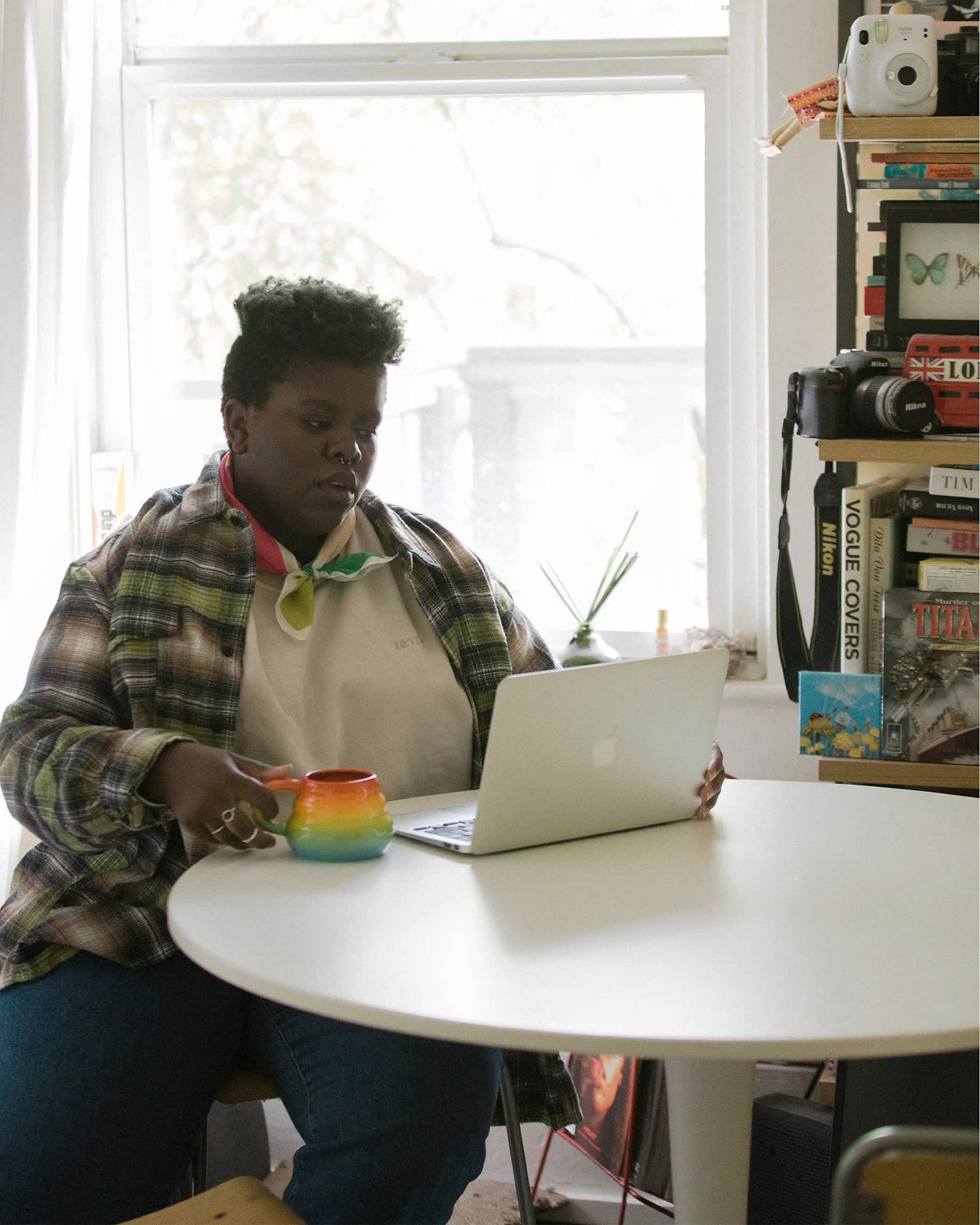 Portrait of Lydia Okello working on their laptop in their home.