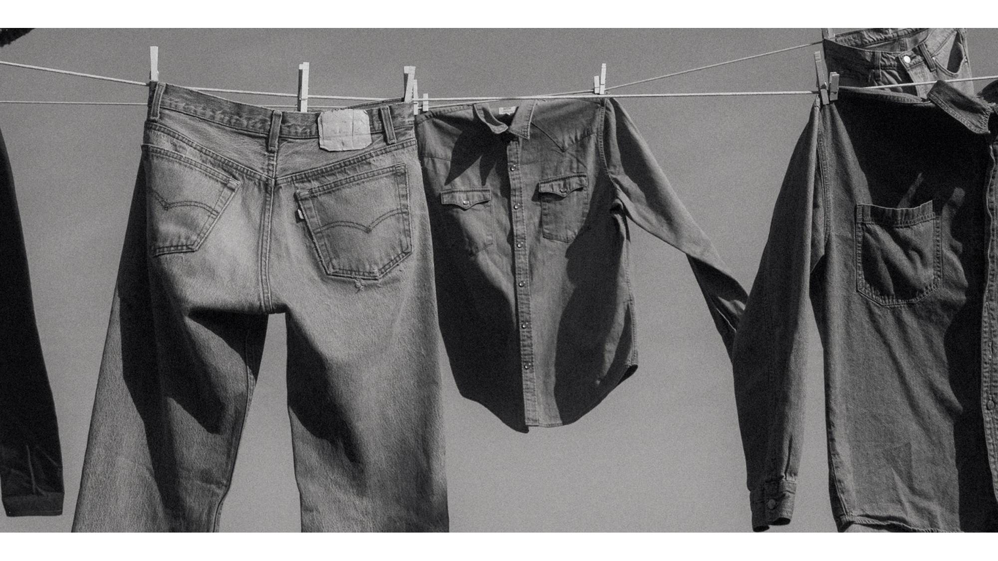 A black and white photo of jeans hanging on a clothing line