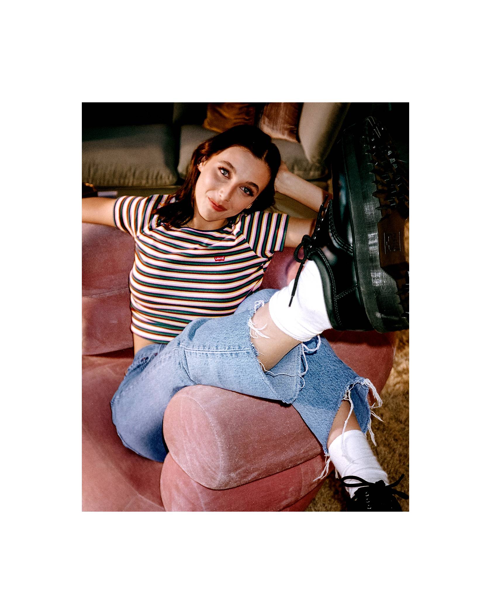 A photo of Emma sitting in a chair wearing a vintage Levi's striped shirt and Levi's jeans