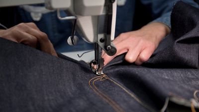 A sewing machine sewing denim