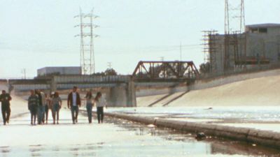 A Gif of Xiuhtezcatl and others walking down a cement waterway.