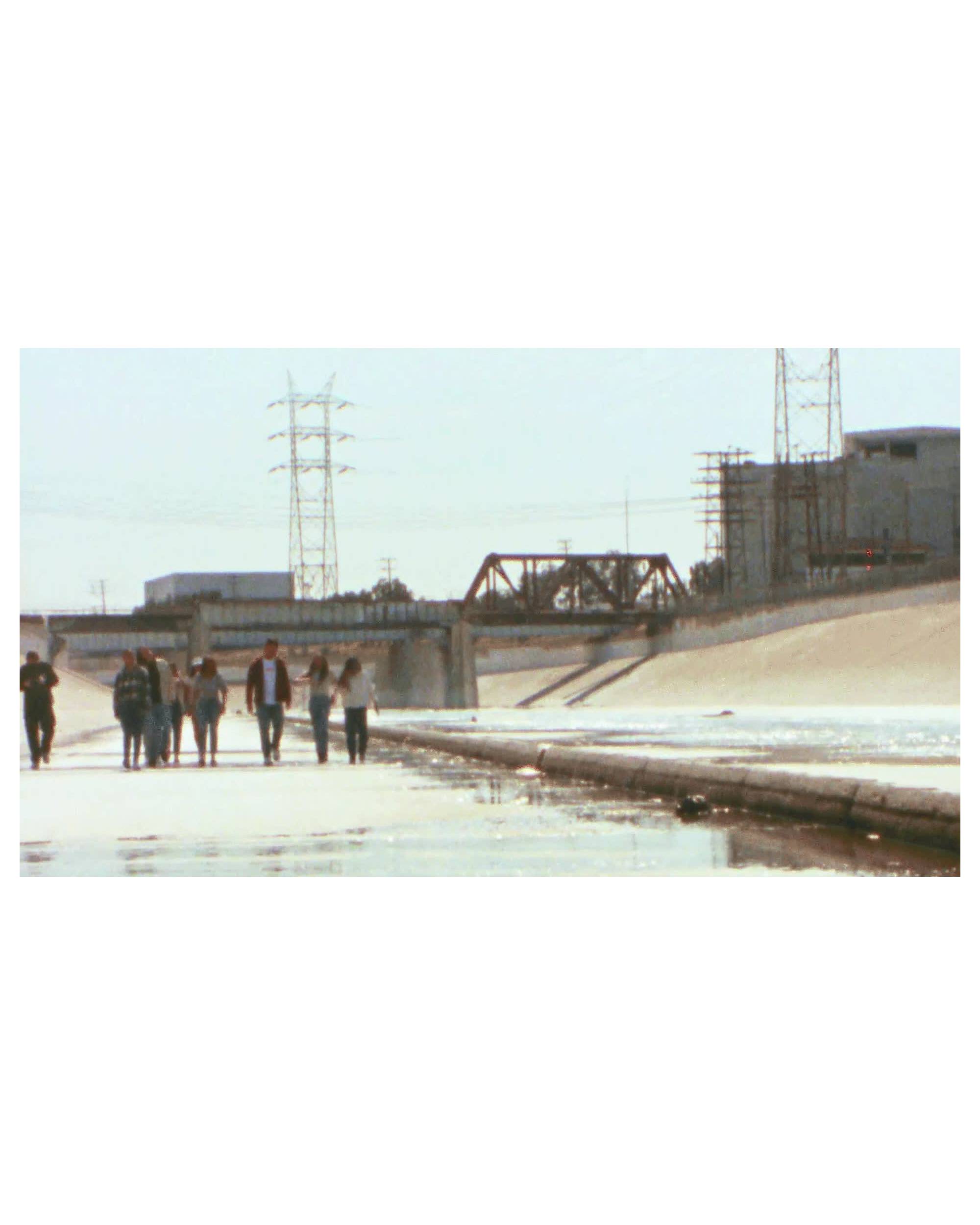 A Gif of Xiuhtezcatl and others walking down a cement waterway.