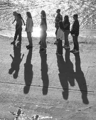 A black and white photo of people standing on the beach