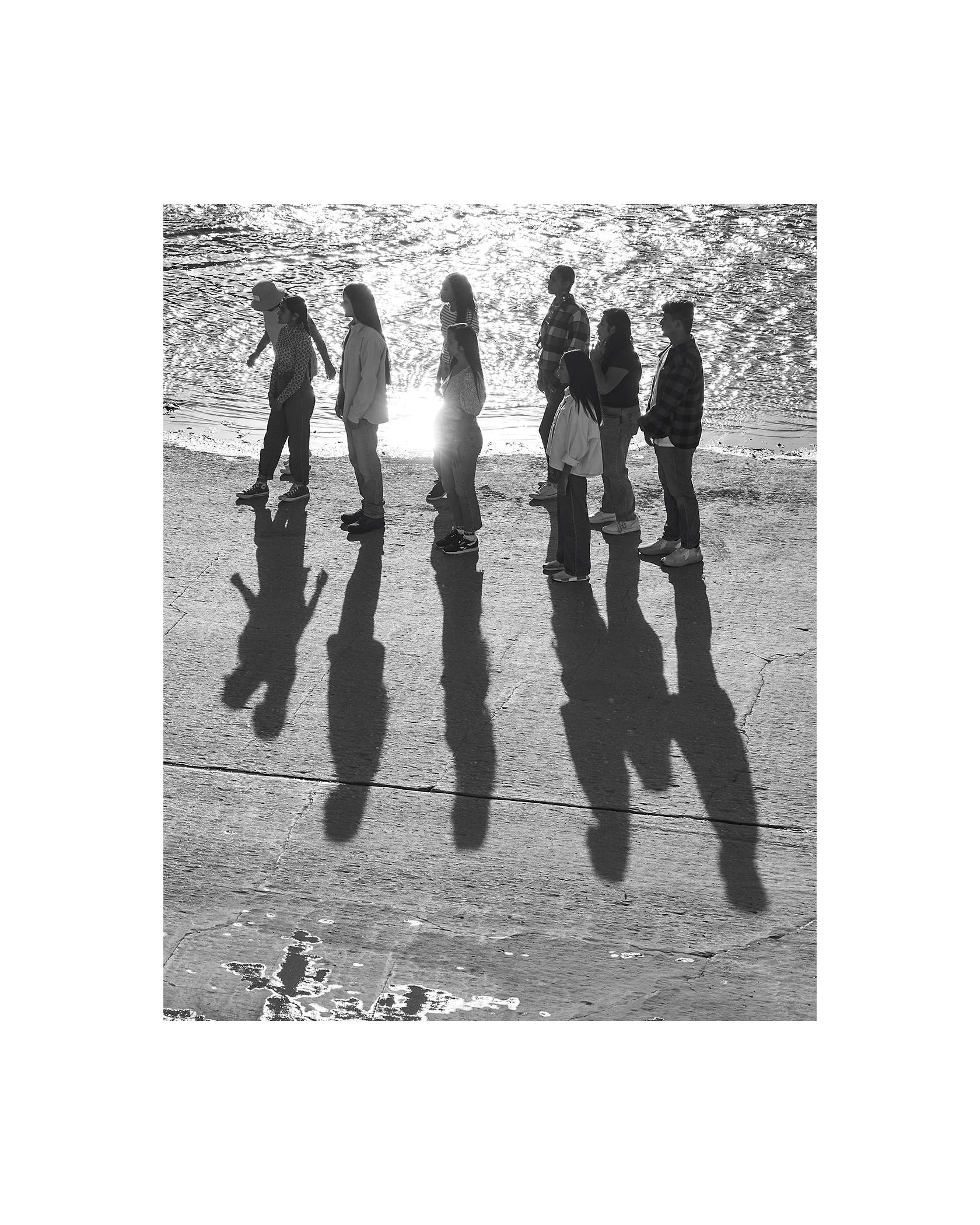 A black and white photo of people standing on the beach