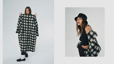 Hailey Bieber holding up a boxy plaid jacket and wearing a black bucket hat.