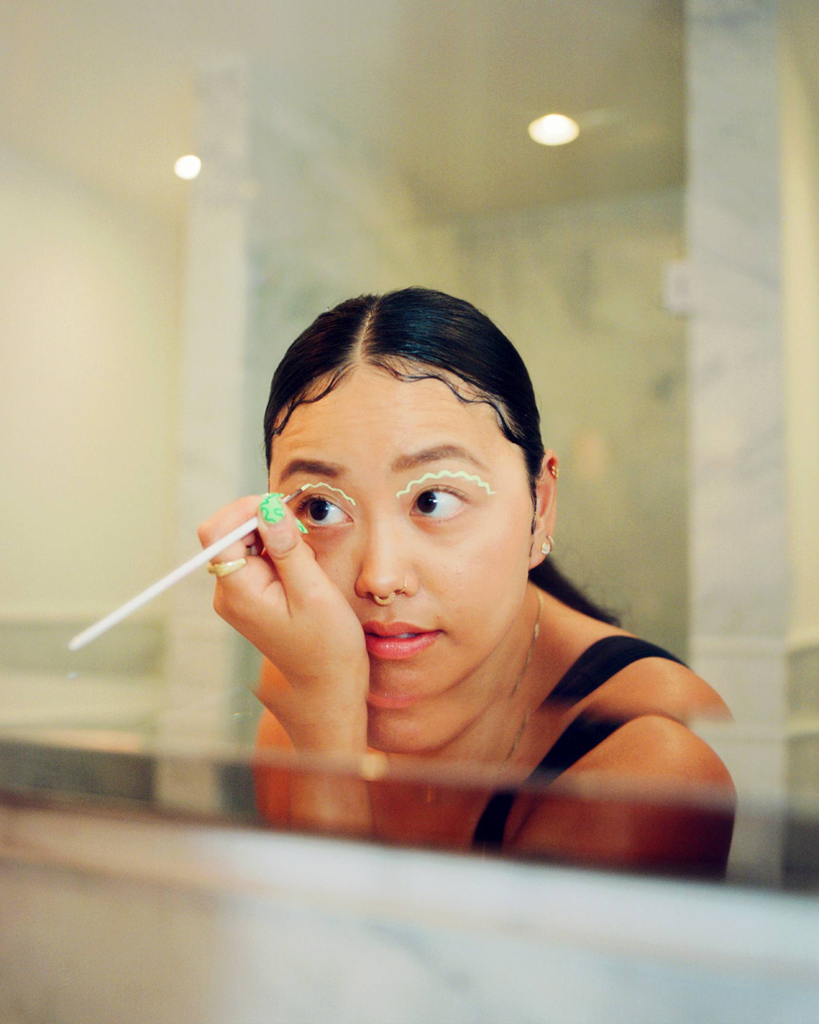 Jezz Chung putting on eye makeup in the mirror