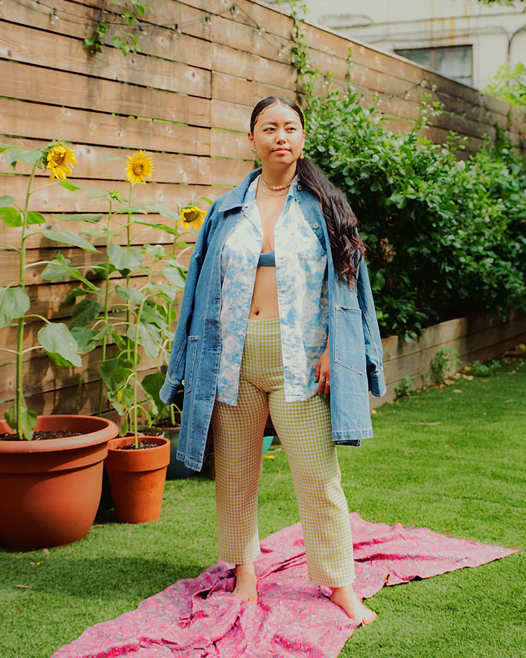 Jezz Chung dans sa cour extérieure dans une chemise western boutonnée en denim de Levis, agencée à un pantalon kaki.