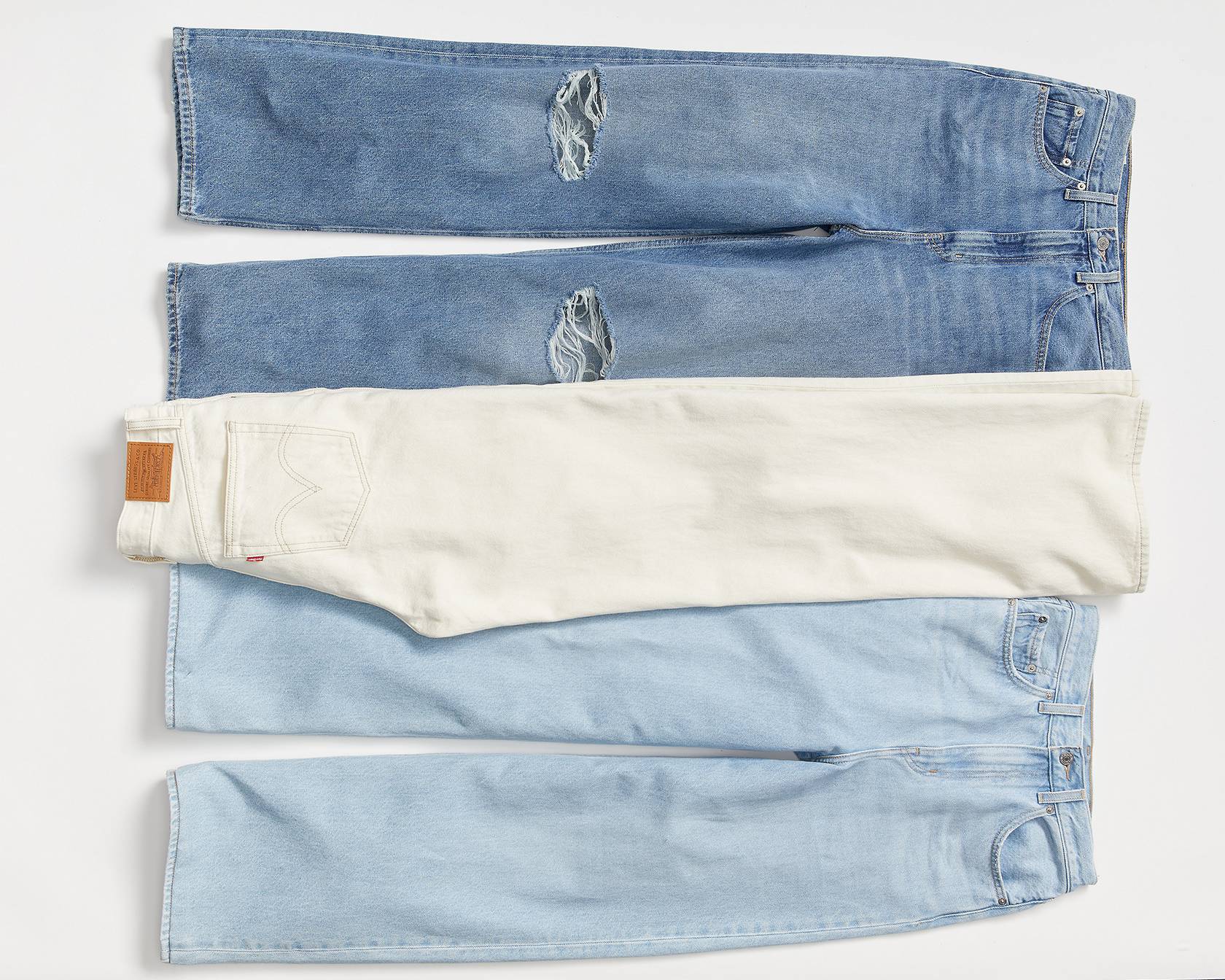 Laydown image of high loose jeans. Dark denim, light denim, and white.