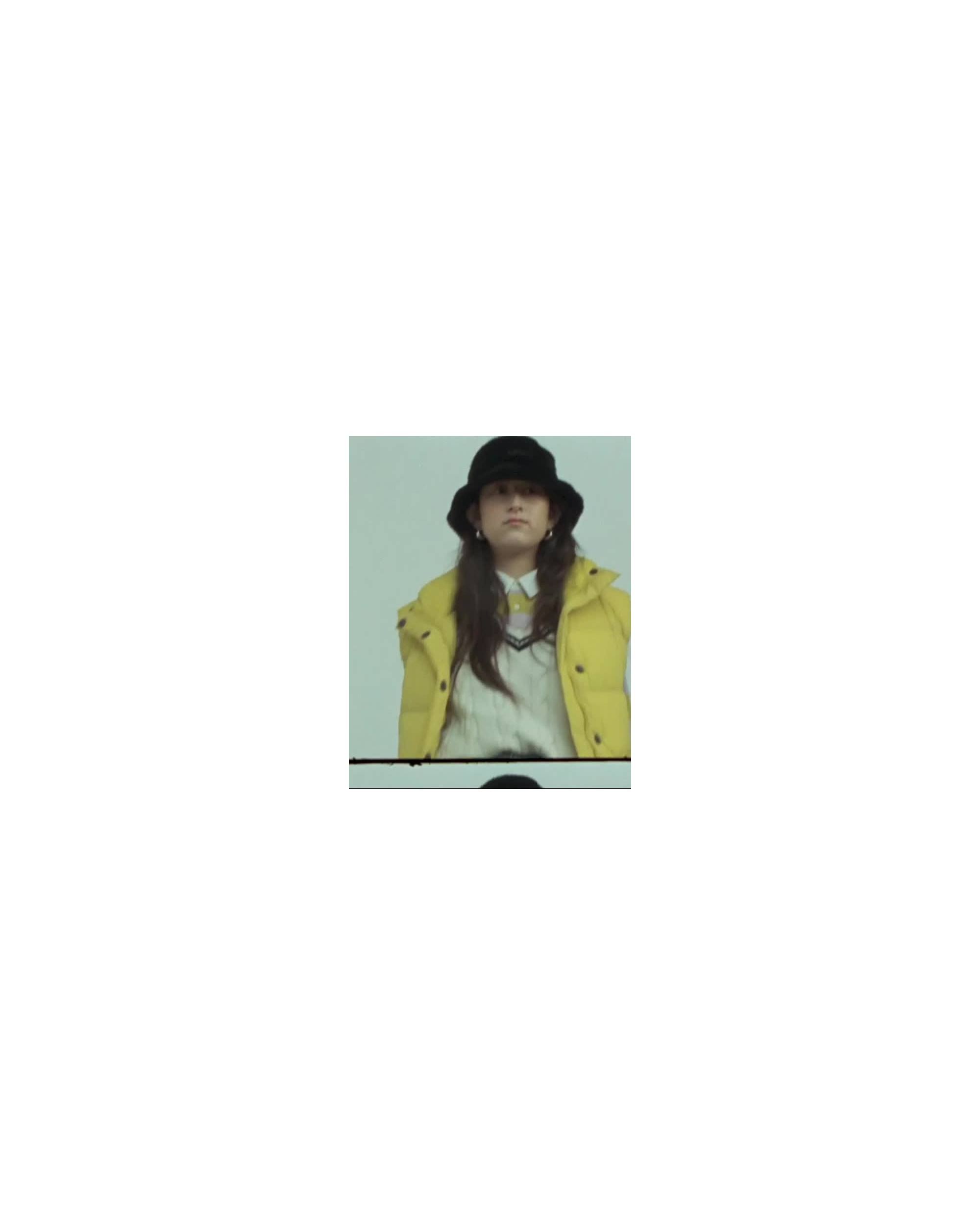 MP4 of woman wearing a yellow puffy jacket and a black bucket hat.