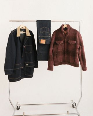 Rack of clothing against a white backdrop that displays some of Gabe's favorite selected items (2 jackets and a pair of blue jeans)