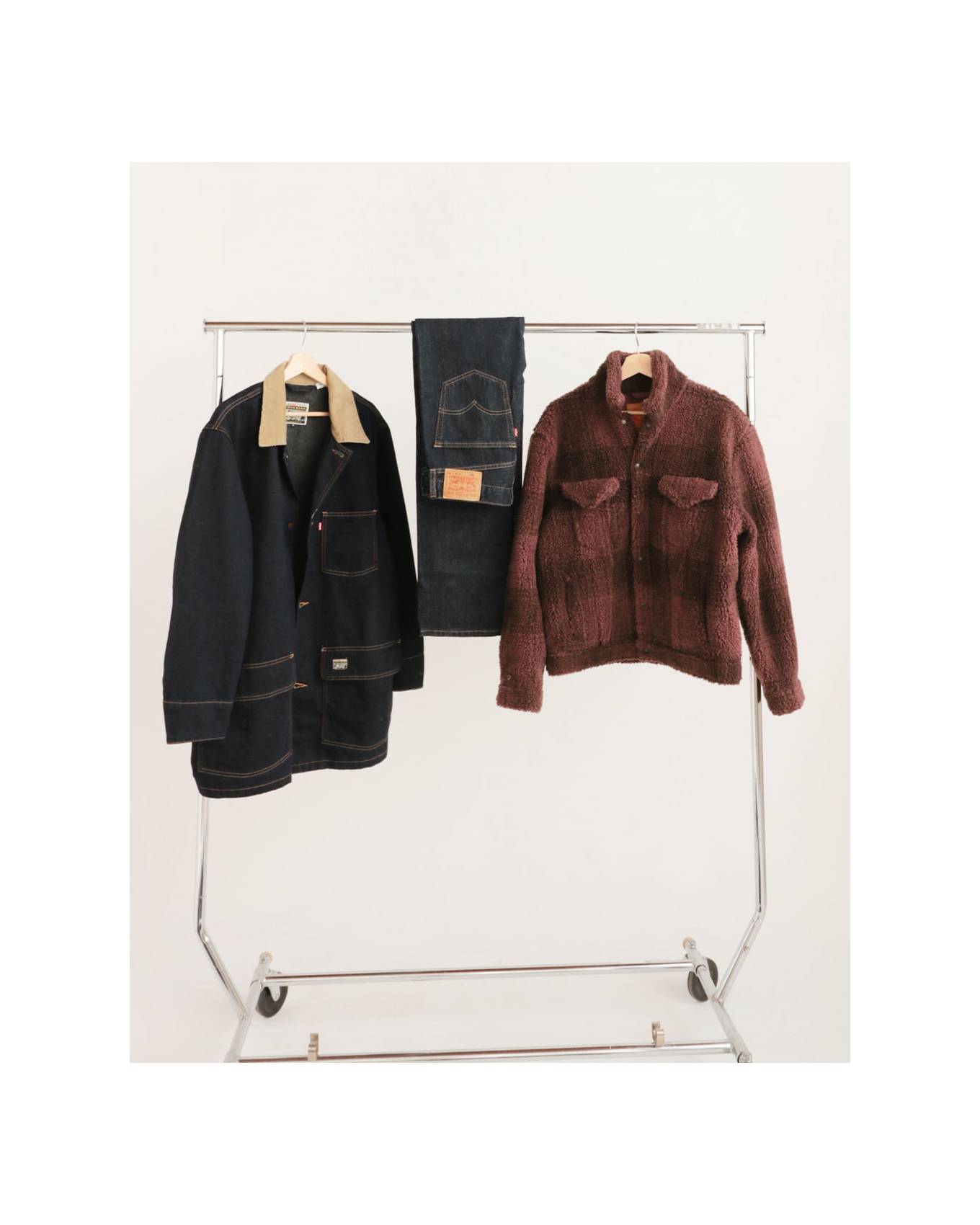 Rack of clothing against a white backdrop that displays some of Gabe's favorite selected items (2 jackets and a pair of blue jeans)