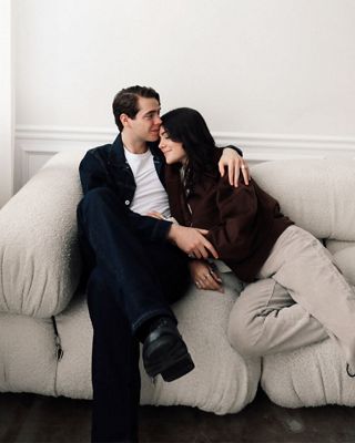 Gabe and Luann cuddling on a cream colored couch wearing neutral colored outfits