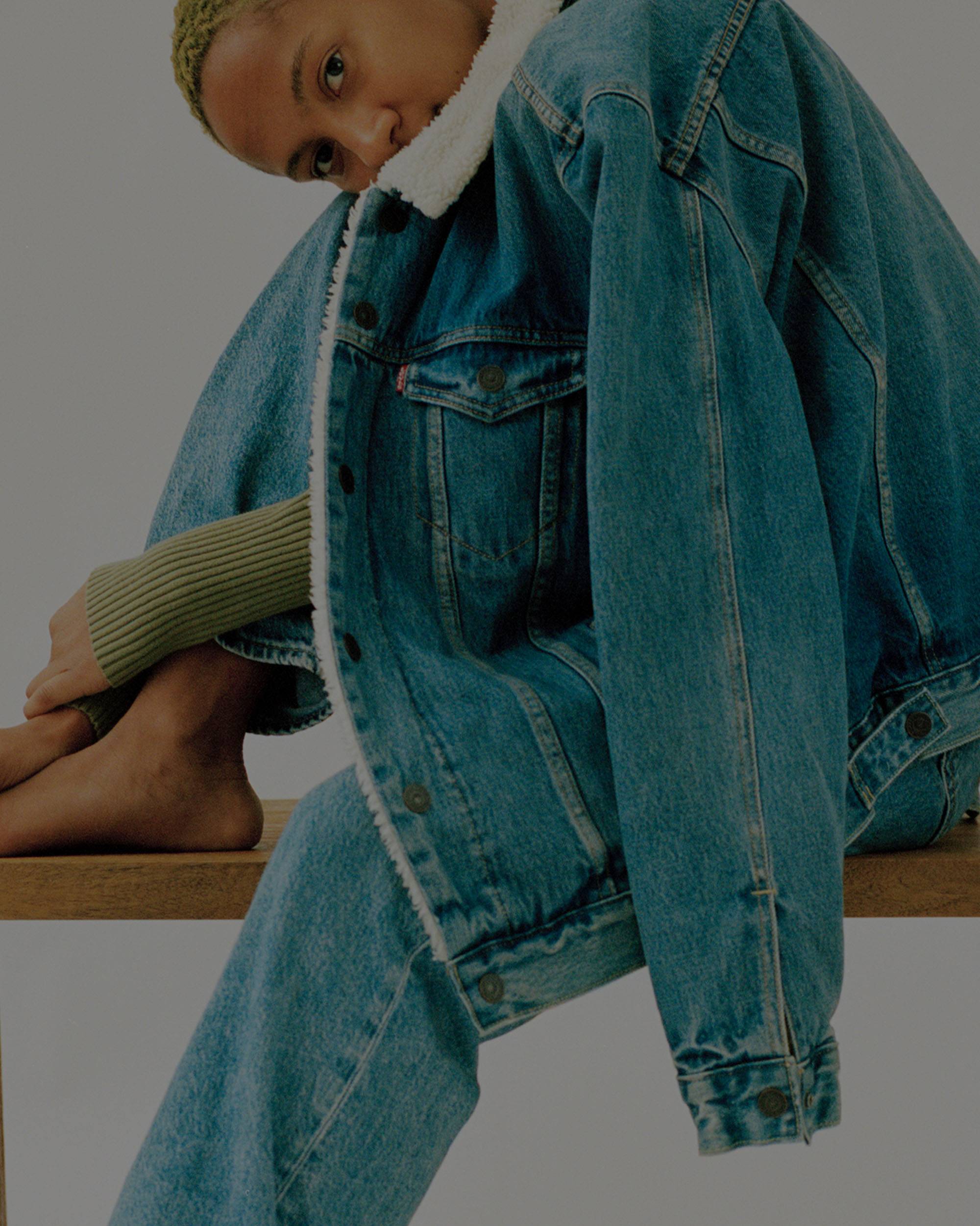 Model in an all denim outfit sitting on a wooden bench
