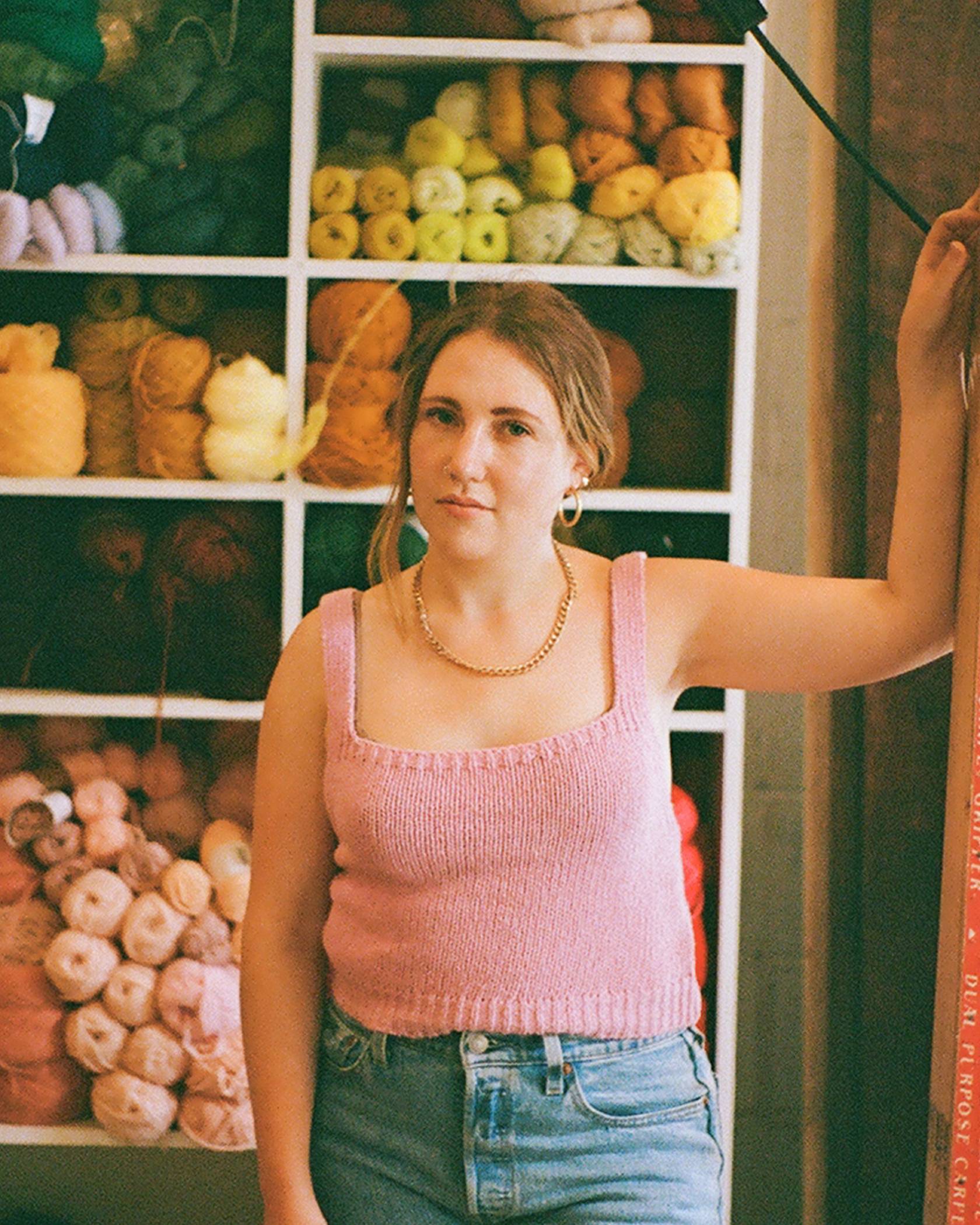 Caroline Kaufman wearing a levis denim jeans and standing in front of a shelve full of different colored yarn