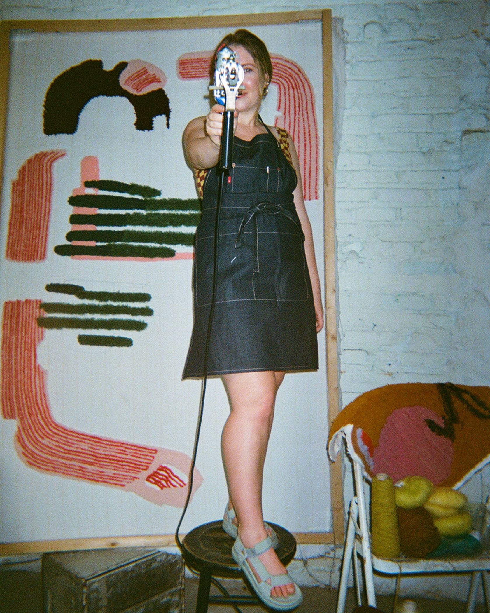 Caroline Kaufman wearing a levis denim overalls in front of her artwork
