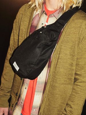 Close up shot of black crossbody bag on model wearing a green cardigan and plaid shirt
