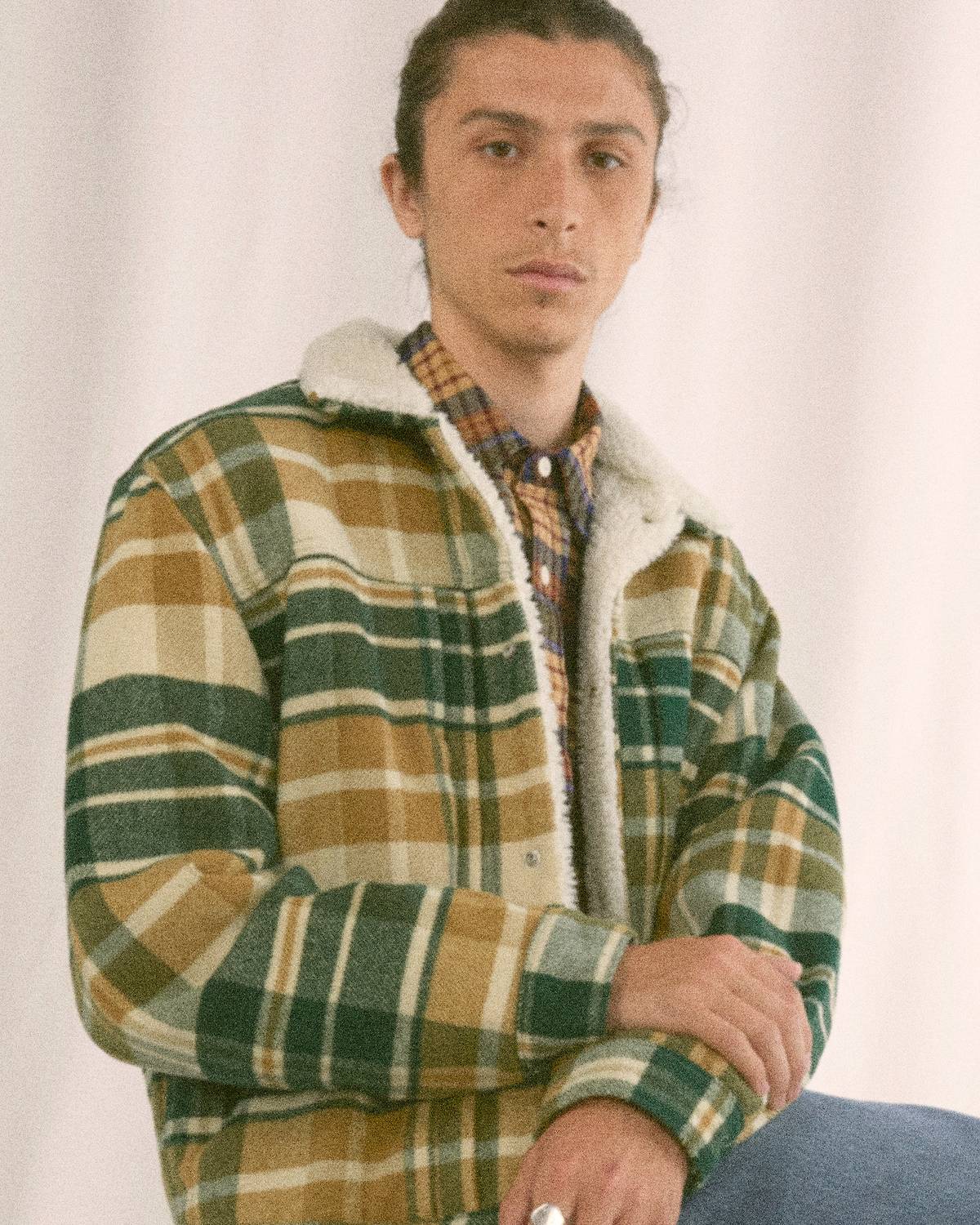 Guy wearing a green, white and yellow patterned sherpa trucker jacket.