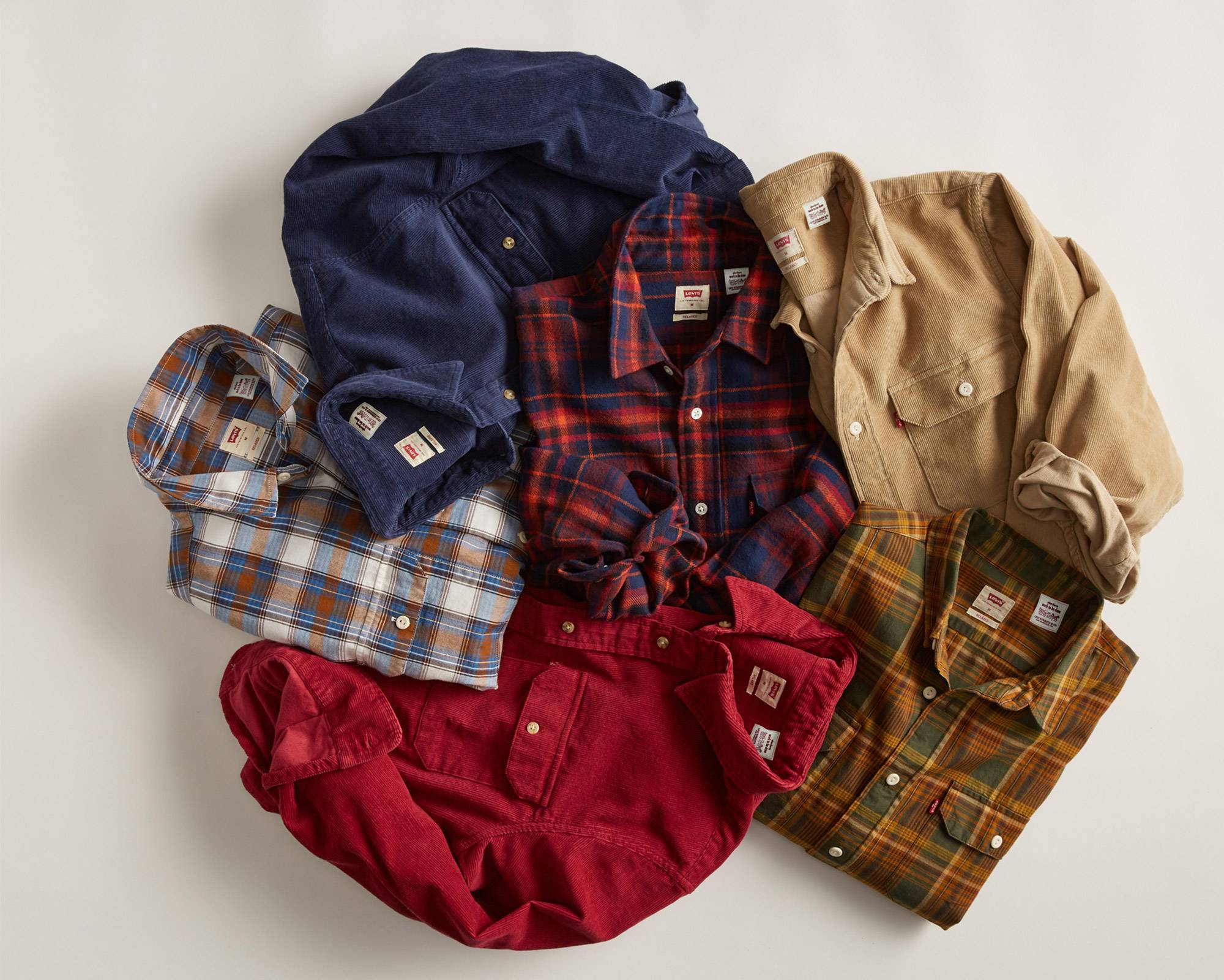Six different button-up shirts that are laid down next to each other, all in different seasonal colors.