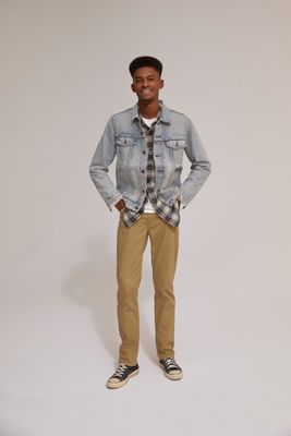Model wearing light wash denim jacket, plaid shirt, and khaki pants