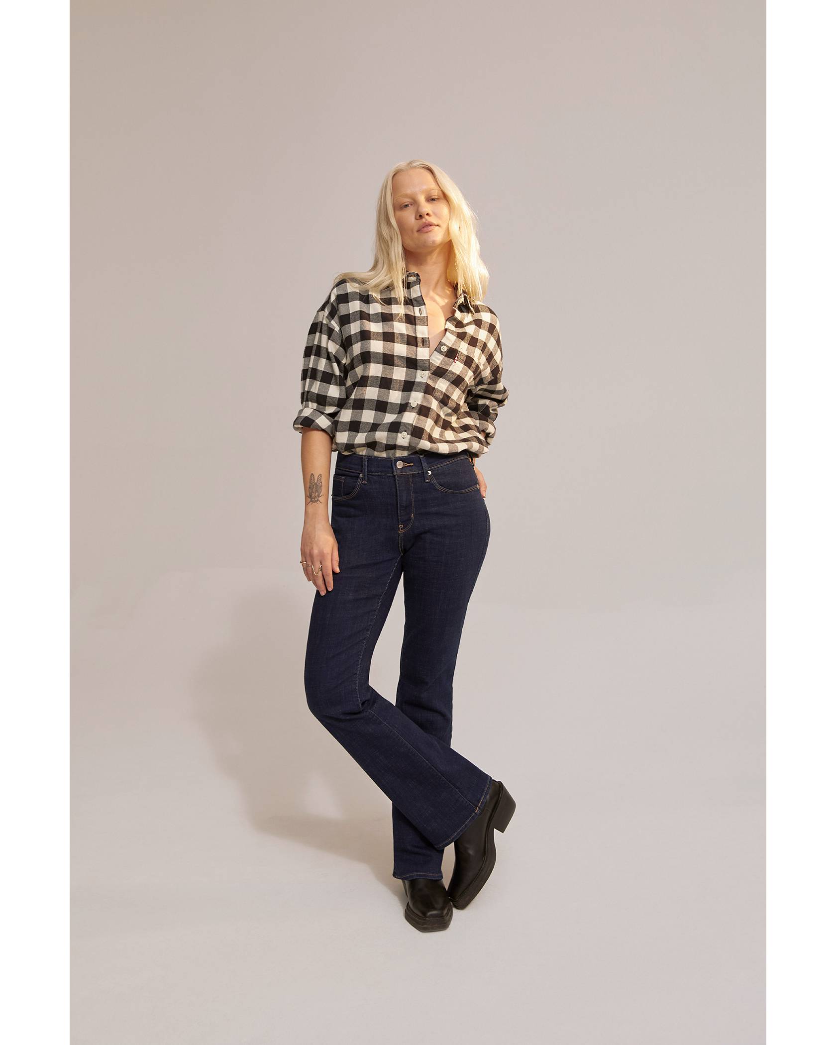 Model wearing black and white gingham shirt and dark wash jeans