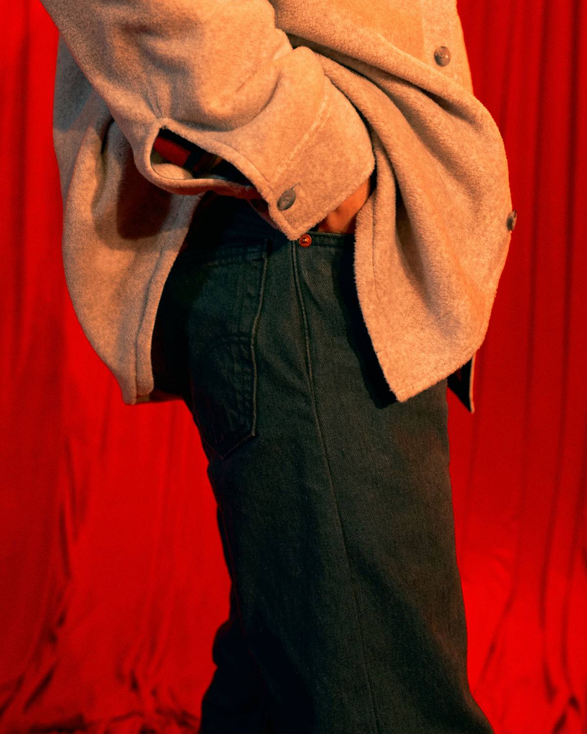 Closeup of a man wearing black 501® Originals against a red curtain back drop