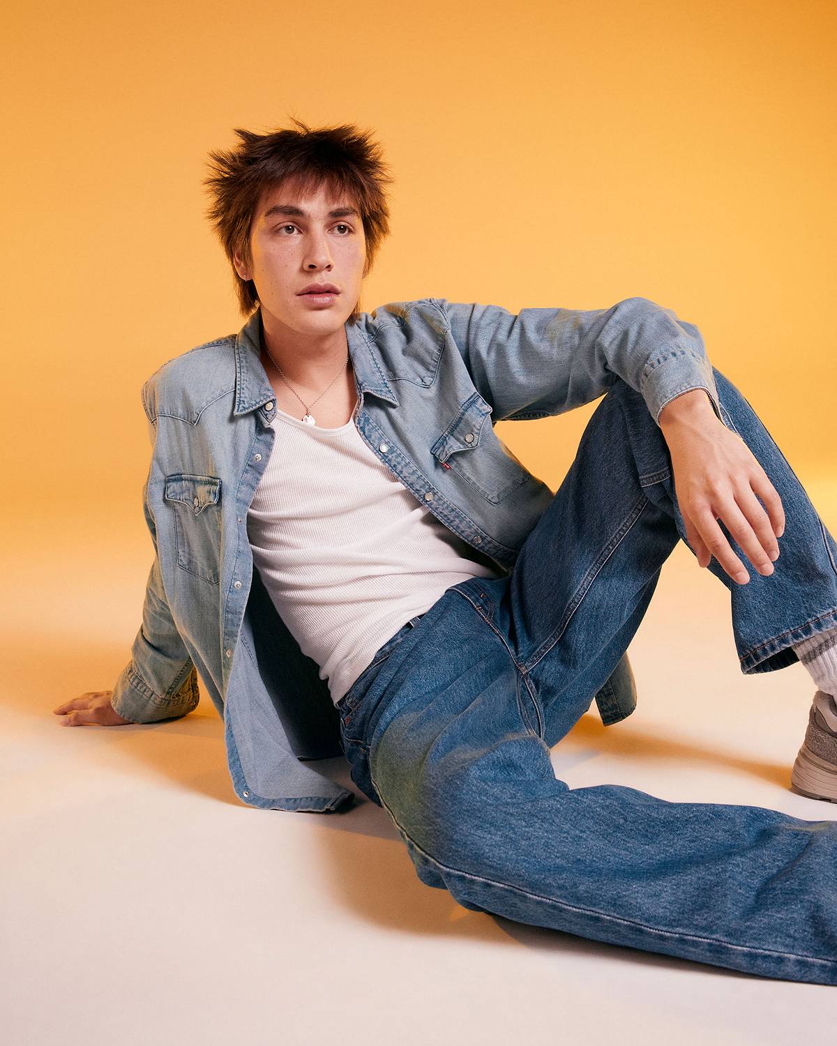 Model against a yellow background in an all denim outfit