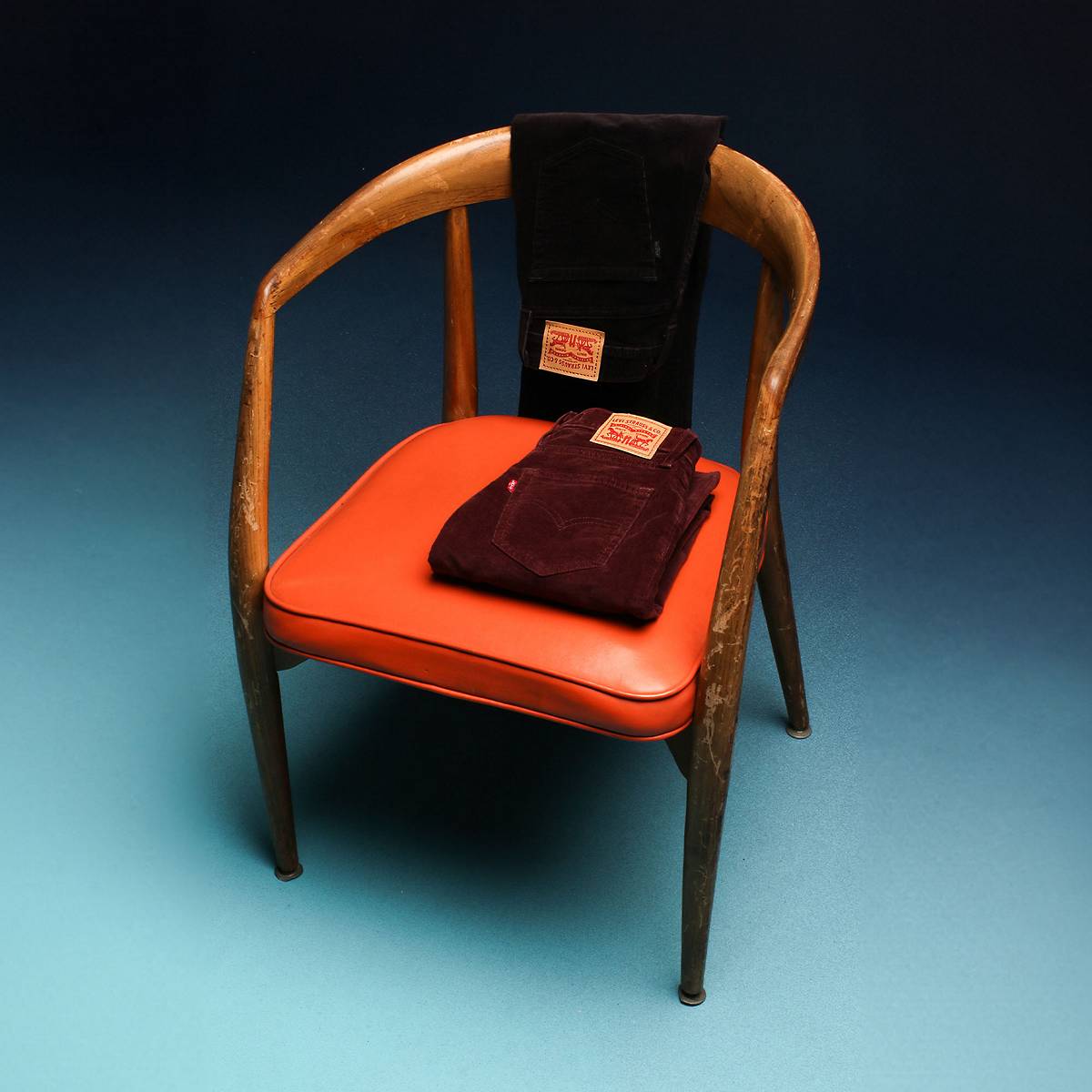 Corduroy pants draped over a chair against a blue gradient background