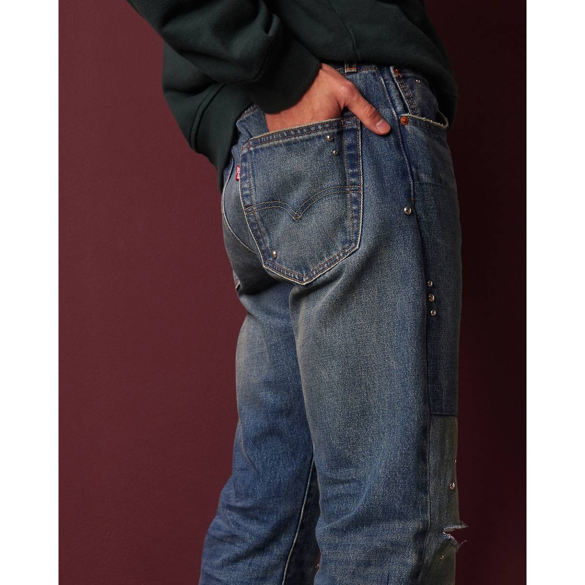 Man wearing jeans behind white wall