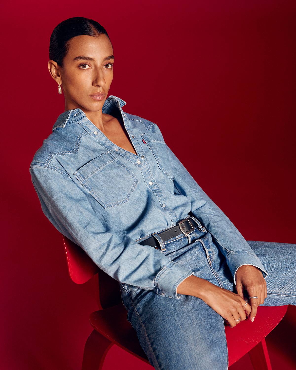 Model in women's denim western button-up against a red background