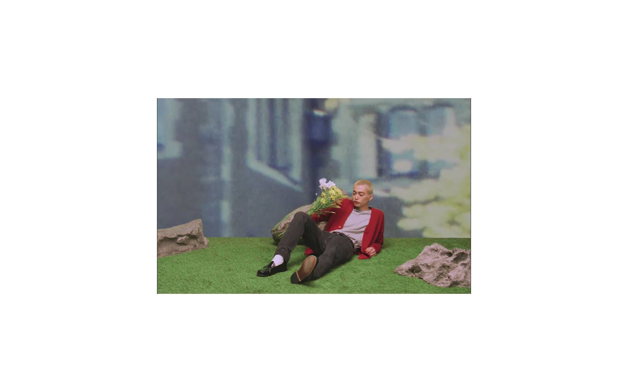 Image of model lounging in a Levi's® cardigan against a grassy landscape 