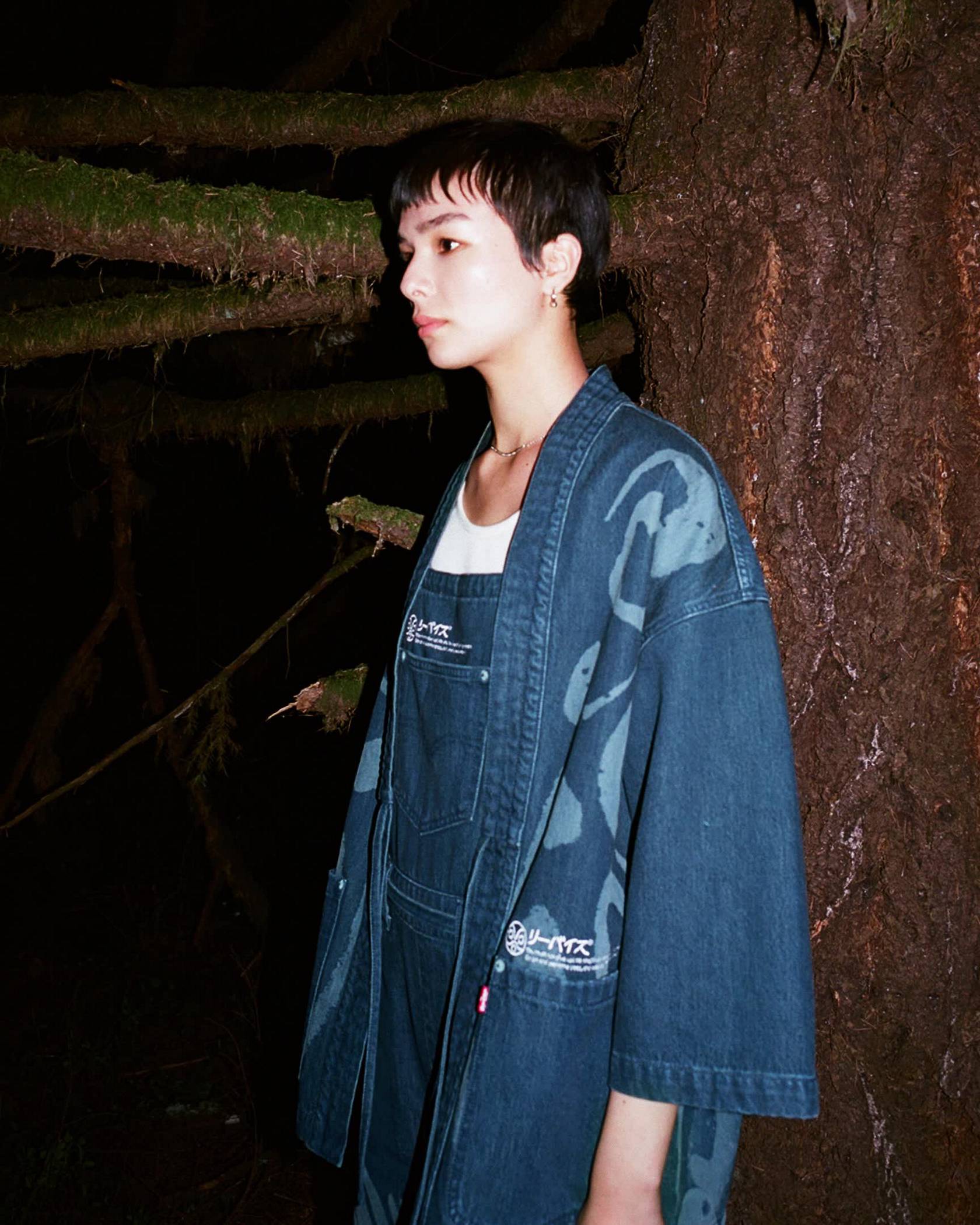 Image of woman wearing Levi's® x Princess Mononoke collection pieces and posing in forest setting
